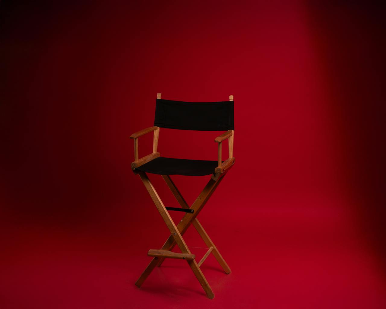 A wooden directors chair against a vibrant red backdrop, symbolizing film industry authority.