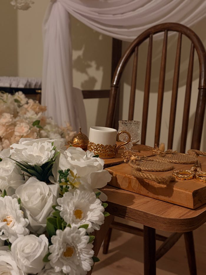A beautifully arranged floral setting with an ornate tea set on a wooden chair, perfect for a traditional ceremony.